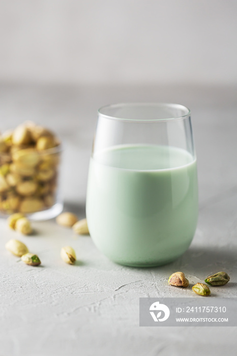 Pistachio milk in the glass on the concrete gray background