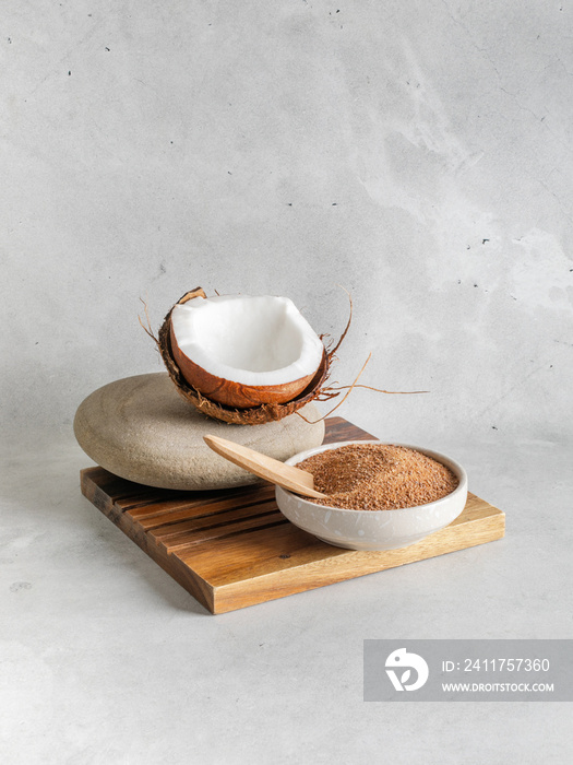 Natural bio brown coconut  sugar in a bowl on wooden stand closeup with coconut  on stone background