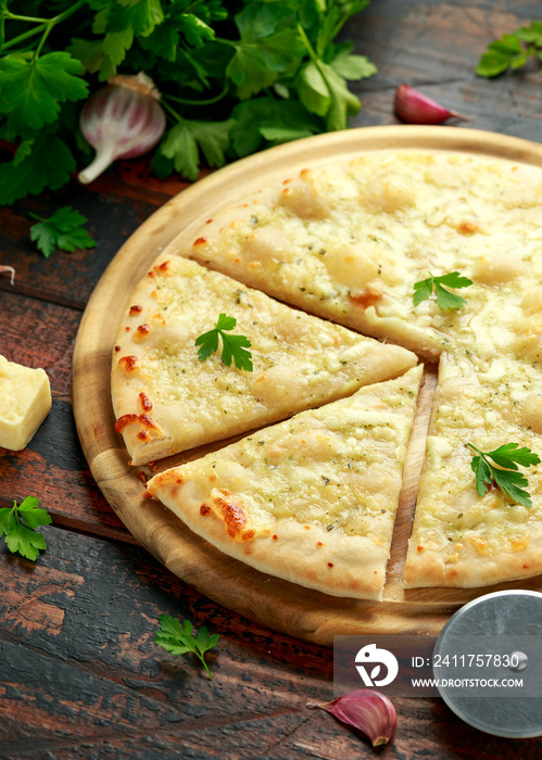 Garlic cheese pizza on wooden board with herbs.