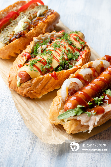 Close up view on different food styled hot dogs with toppings on light wooden background. Flat lay street food. Copy space for design. Hot dog american fast food. Food background