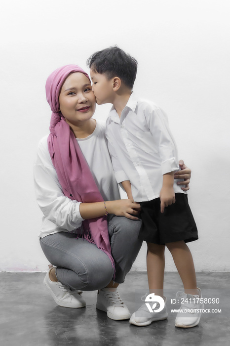 Young adult female cancer patient spending time with son at home, relaxing on the couch. Cancer and family support concept.