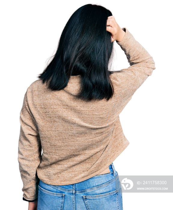 Young chinese woman wearing casual sweater and glasses backwards thinking about doubt with hand on head