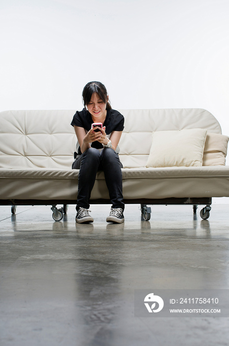 Young woman sitting on sofa using smartphone