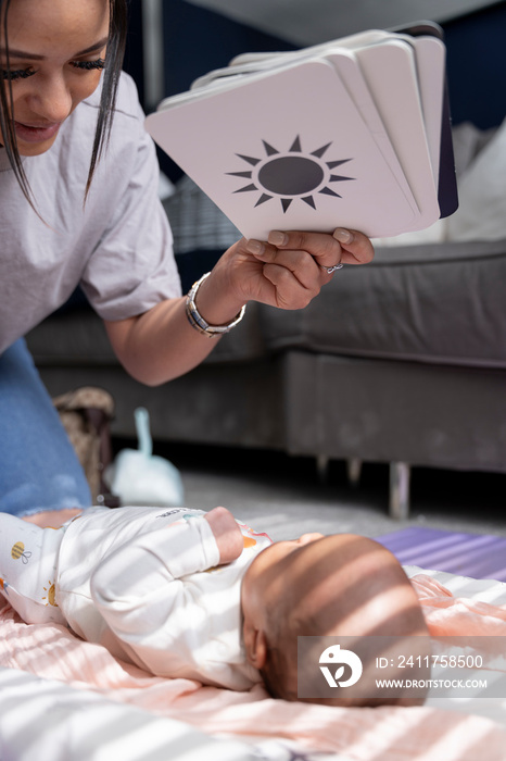 Mother showing contrast cards to newborn baby girl at home