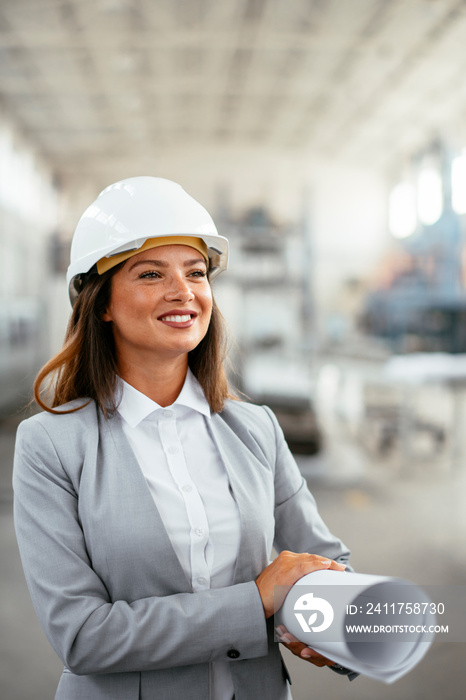 Young businesswoman with blueprint. Portrait of female architect in factory.