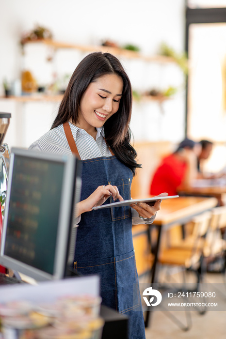 Portrait of a Asian beautiful smiling female starting small business owner with tablet near counter in her cafe.