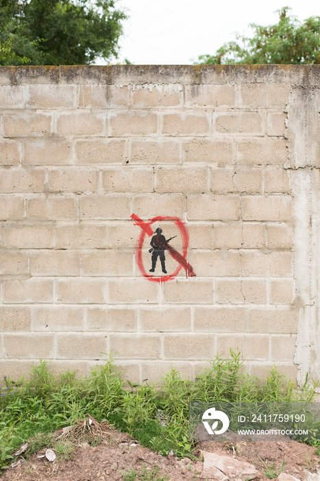 Concrete block wall with a painted symbol: a black military silhouette crossed out with red