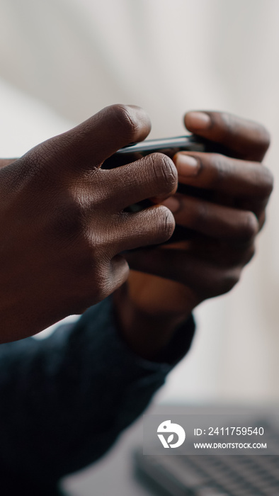 Close up of black man hands playing online internet mobile video games on his phone at home. Leisure entertainment time, gaming in free time on web services