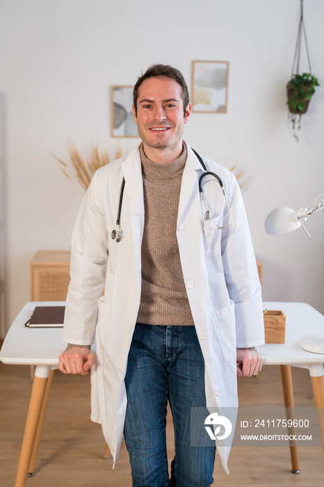 Cheerful doctor standing at his modern clinic