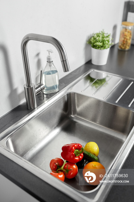 hygiene, food and safety concept - fruits and vegetables in stainless steel kitchen sink