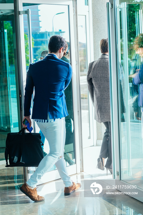 Businesswoman and her male colleague leaving the office building with glass doors.