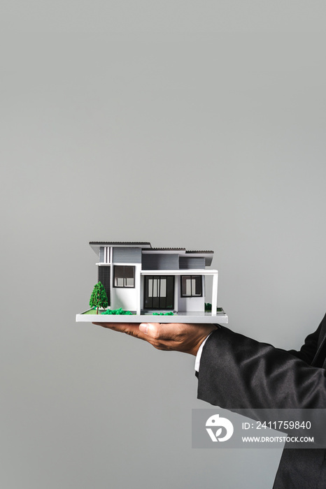 Businessman holding home model modern design. Loan and real estate concept.