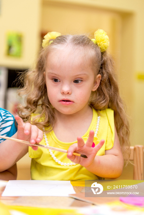 Girl with Down Syndrome draws on paper a rehabilitation center for special children