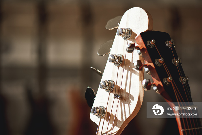 Close-up view of two different guitar headstocks with tuning keys against of a blurred background