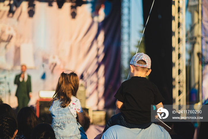 Boy sitting on daddy’s shoulders at a concert