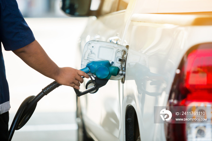 Hand refilling the white pickup truck with fuel at the gas station