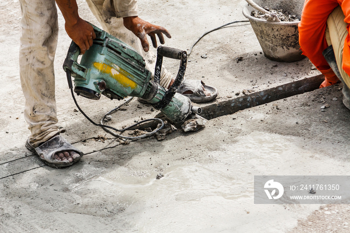 Construction worker using jackhammer drilling concrete surface