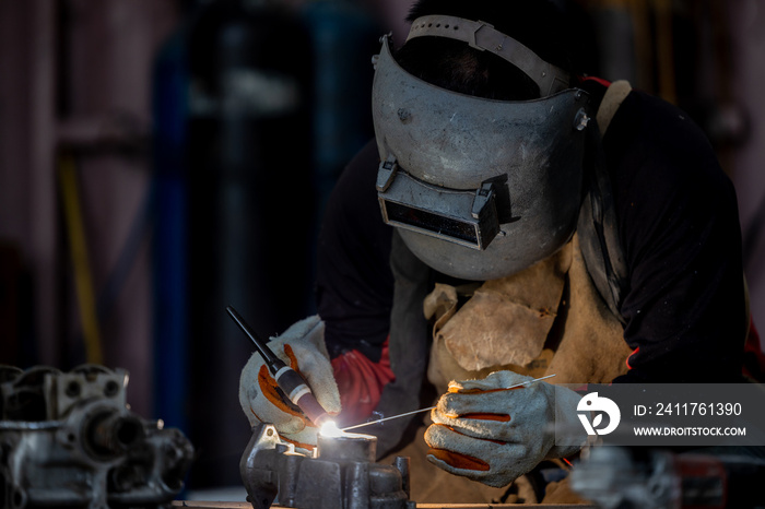 Welder in face mask welds with argon arc stainless steel welding, Industrial worker at the factory welding steel structure, Welder is welding Tungsten Inert Gas.