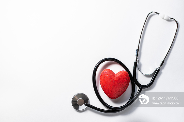 Medical stethoscope and red heart isolated on white background top view, copy space for your text. Heart diseases prophylaxis concept. Health care concept.