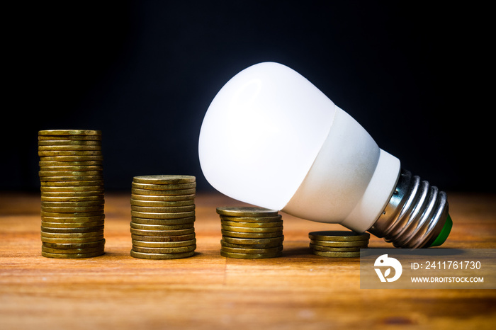 Stacks of coins with led spotlight above, electricity consumption, price reduction.