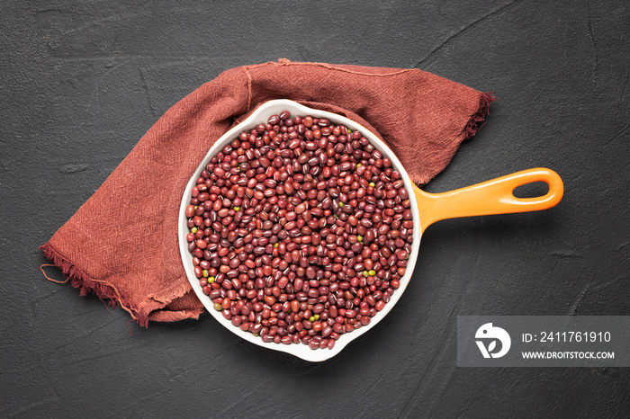 bowl with azukis red beans on black background and red kitchen towel