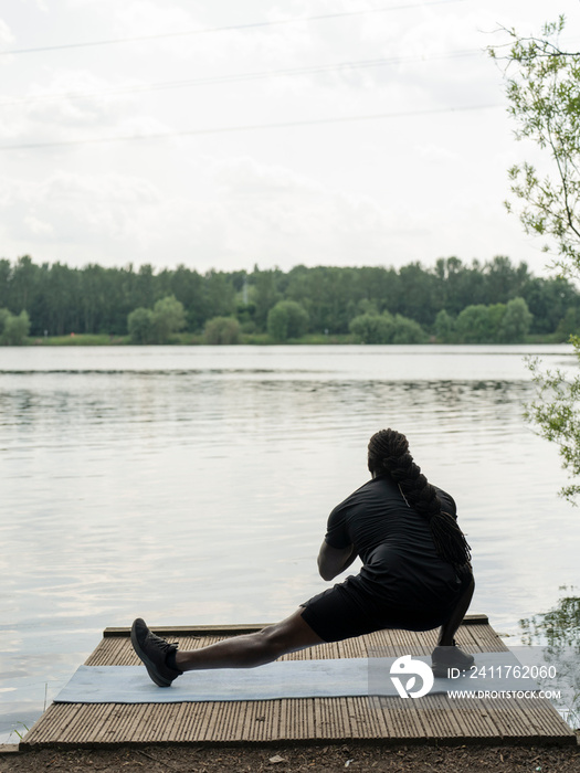 Man practicing yoga by lake