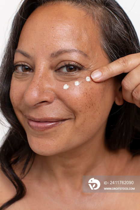 Studio portrait of smiling woman with dots of eye cream