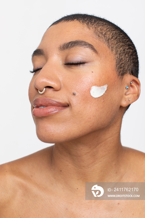 Studio portrait of woman with face cream on cheek