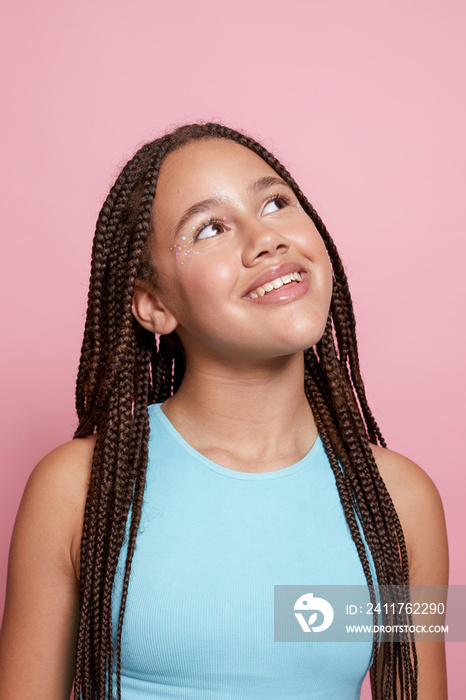 Studio portrait of smiling girl with braids and decorative stickers on face