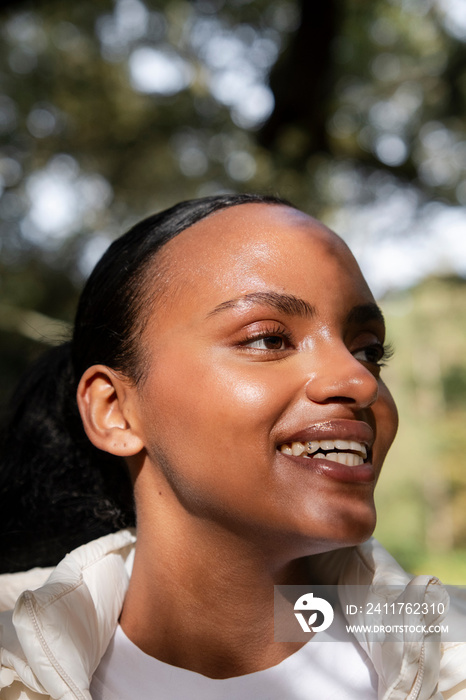 Portrait of smiling woman relaxing in park on sunny day