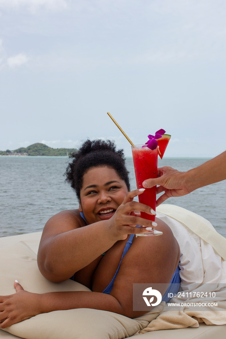 Young woman taking cocktail and relaxing near bay