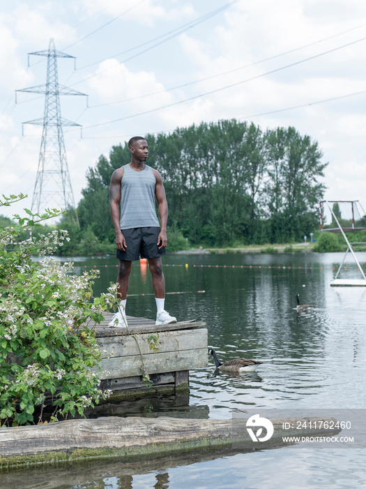 Muscular man in sports clothing standing by lake