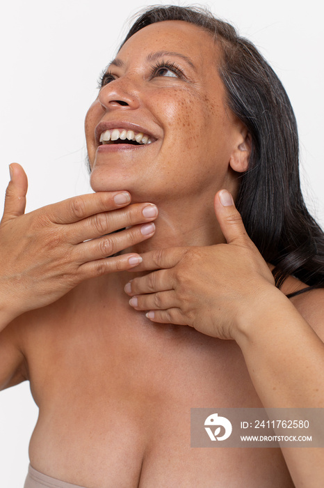 Studio portrait of smiling woman massaging neck