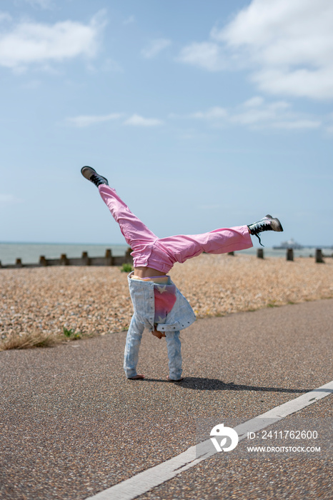 Girl (8-9) in colorful clothes doing cartwheel outdoors