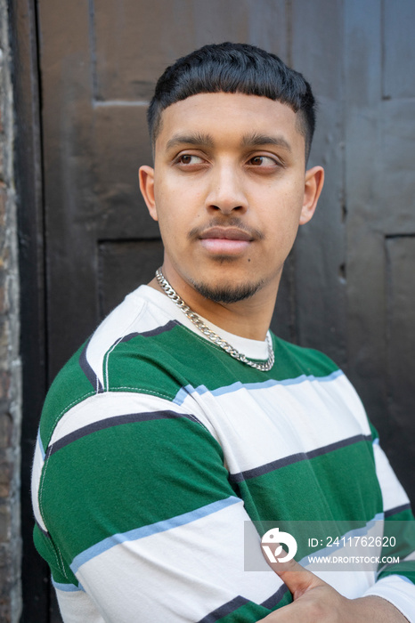 Portrait of young man wearing striped sweatshirt and looking away