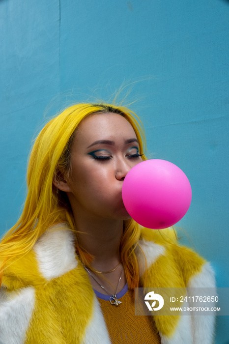 Young woman with yellow hair blowing bubble gum