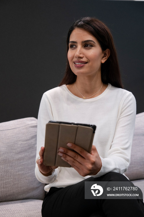 Woman sitting on sofa and using digital tablet