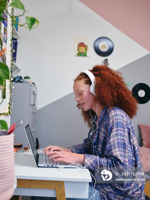 Girl using laptop with headphones at home