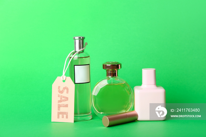 Perfume bottles with lipstick and sale tag on green background