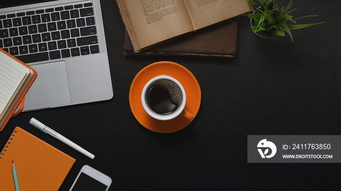 Top view image of Computer laptop, Coffee cup, Books, Potted plant, Notebook, Diary, Pen and Smartphone putting together on black leather desk. Vintage workplace concept.