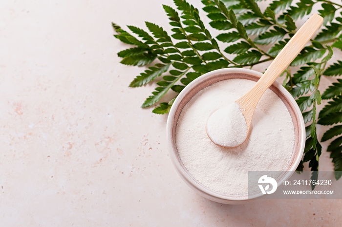 Collagen powder and spoon on beige stone background, top view