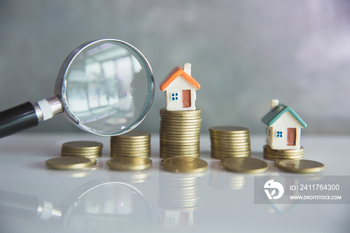 Miniature of house with magnifying glass and coin,  choice of location for the construction, of mortgage, rental housing, House searching concept.