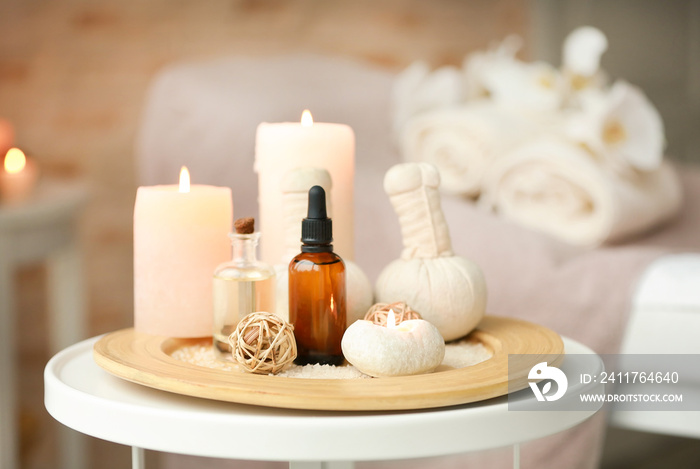 Bottles of essential oil, sea salt and candles on wooden tray