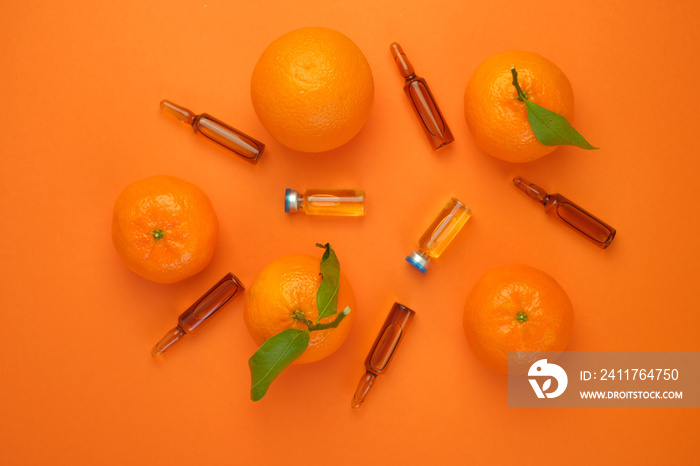 Vitamin C concept. Tangerines citrus fruits, vitamin C in glass ampoules on a bright orange background.ampoules and Serum with Vitamin C. Organic cosmetics concept. Medicine and health concept.