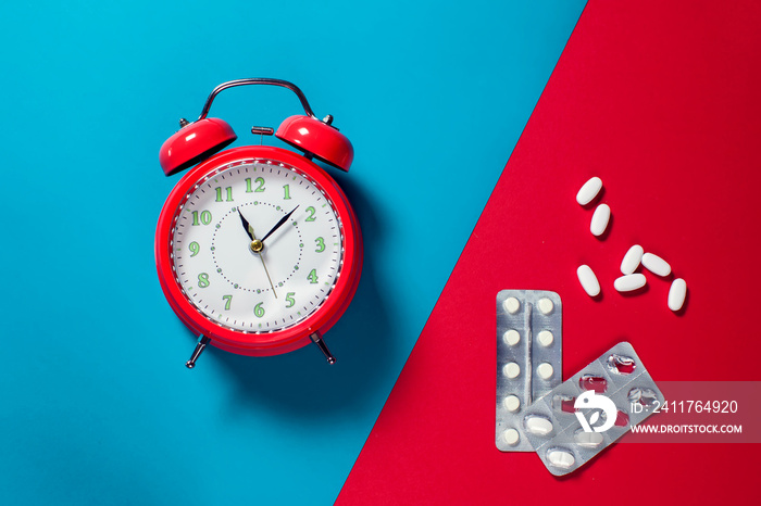 Alarm clock and pills on the color background. Healthcare and medicine concept