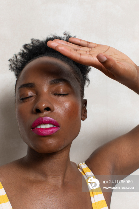 Woman with closed eyes shielding face with hand