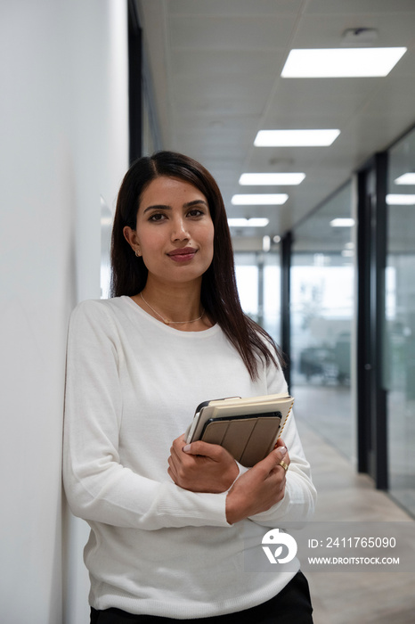 Portrait of businesswoman standing in office corridor