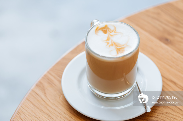 Caffe latte in transparent mug with other mug in first plan, blurred. Barista coffee for international barista day. Break and pause to chill. Coffee with milk and foam.