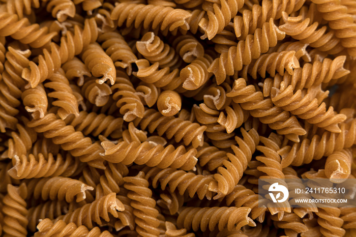 Dry whole grain or integral pasta background top view. Dry integral fusilli top view.