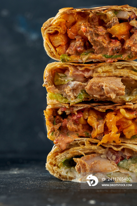 Shawarma stacked one on top of the other with meat and vegetable filling. A stack of shawarma on a dark background. Selective focus